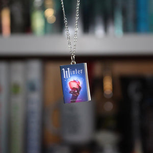 Winter Miniature Book Necklace in front of book shelves