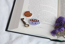 Load image into Gallery viewer, Cookie and Hot Chocolate Magnetic Bookmark on a book page with a key