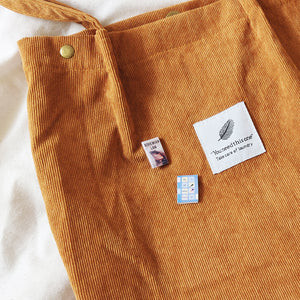 Two All the Bright places miniature book badges pin on a orange tote bag